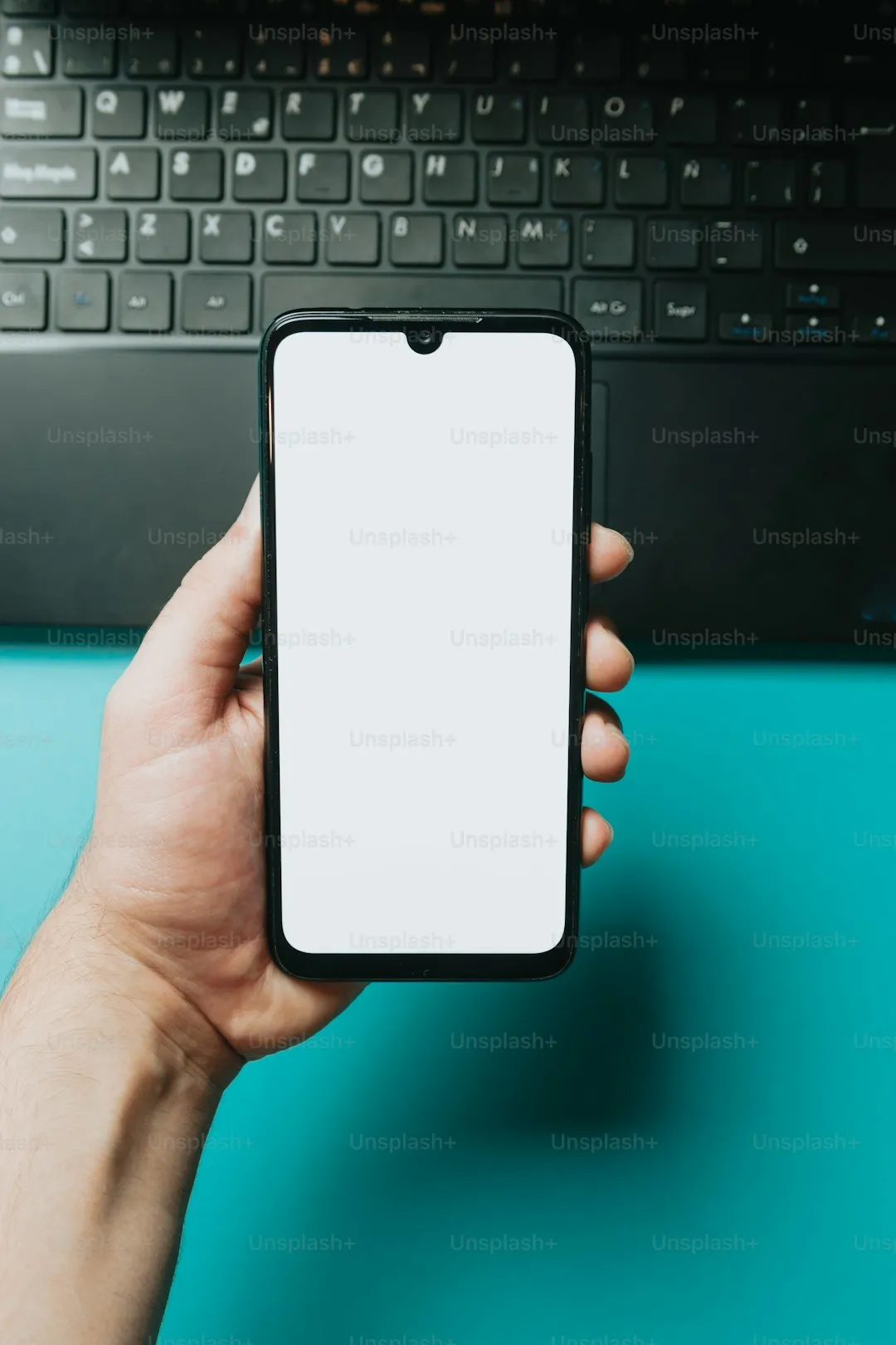 ノートパソコンの前でスマートフォンを操作する手元