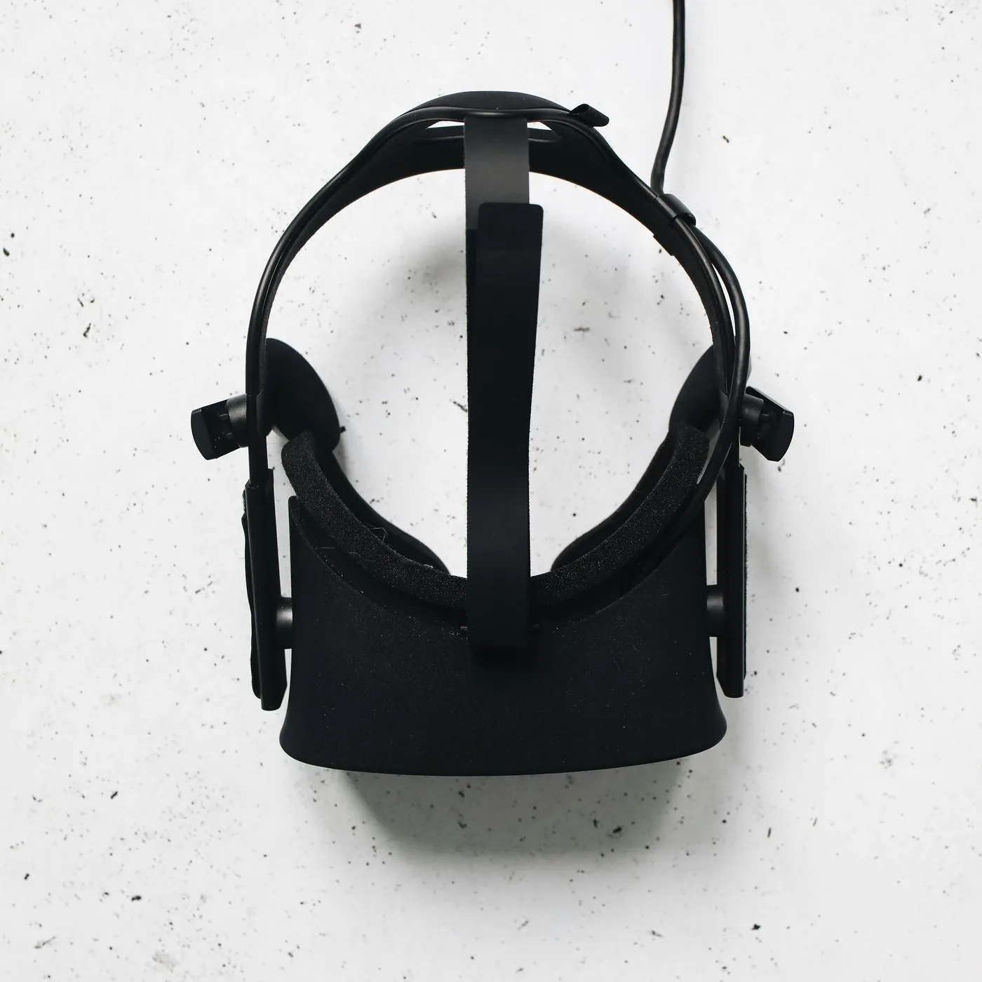 白い面の上に置かれた、ケーブルのついた黒いVRヘッドセット