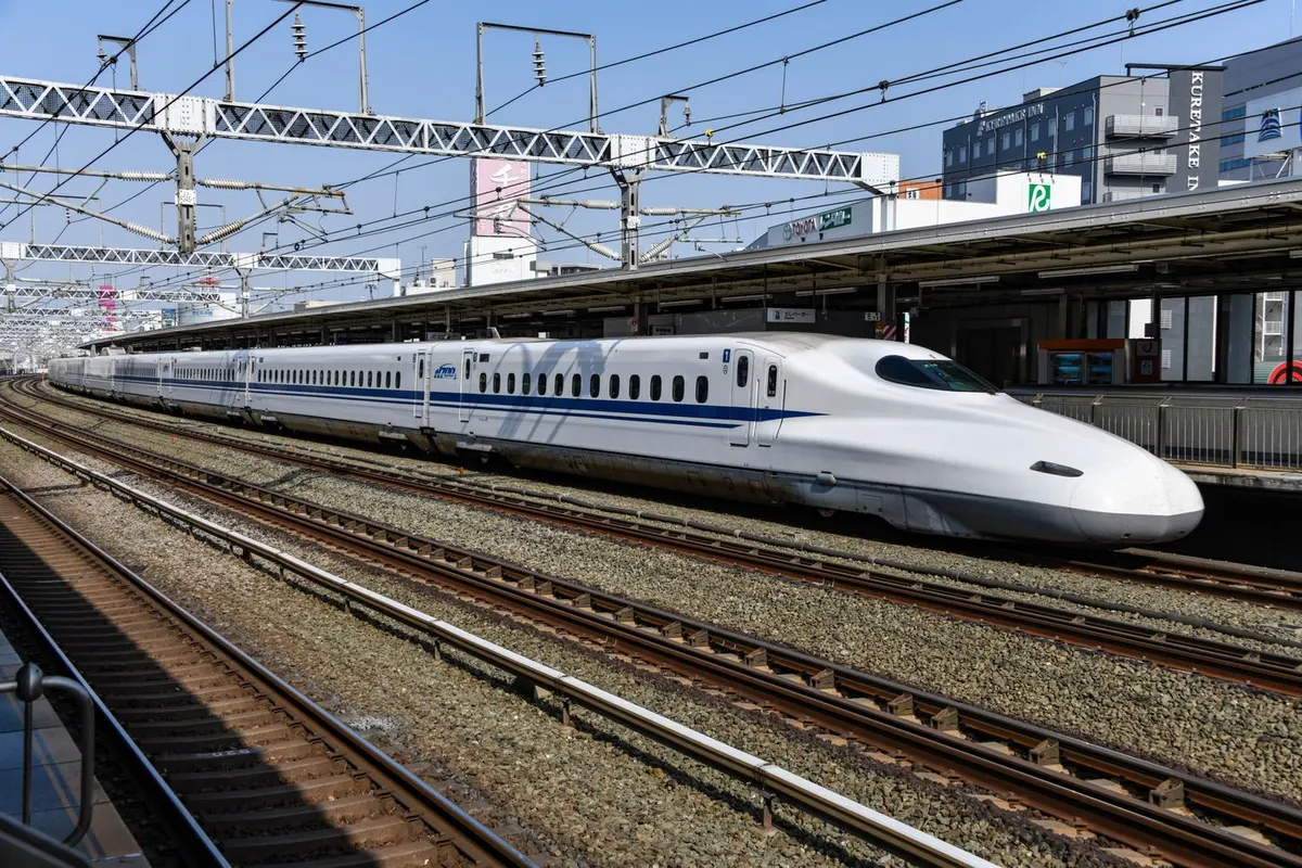 駅のホームに停車している白い新幹線と線路