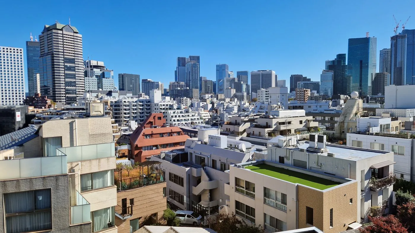 青空の下、高層ビルと集合住宅が密集する東京の街並み